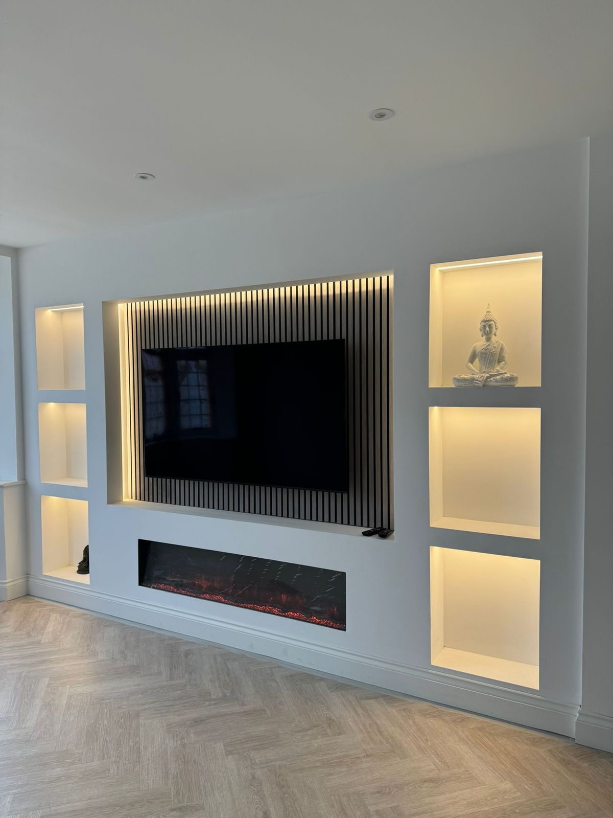 Slatted panel media wall with integrated fireplace and lit niches in Leicester